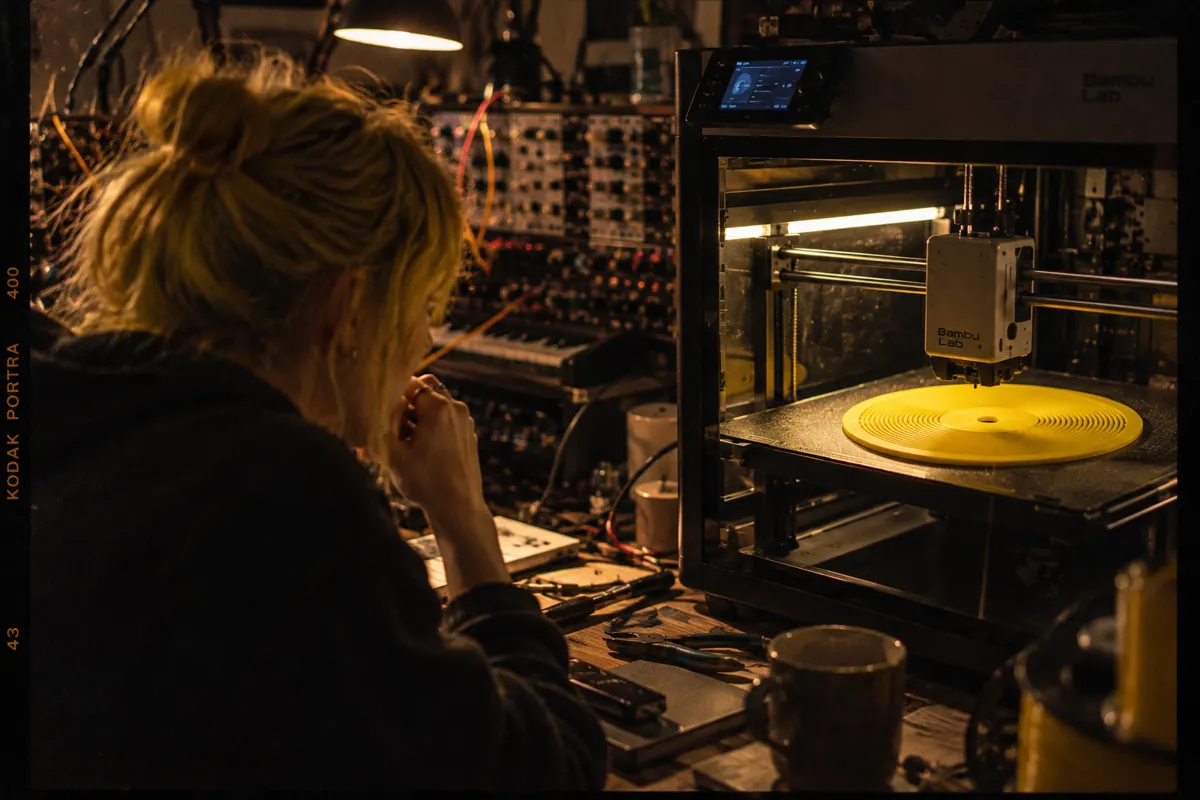 A maker watches a yellow Kräftsound disc being printed in her studio
