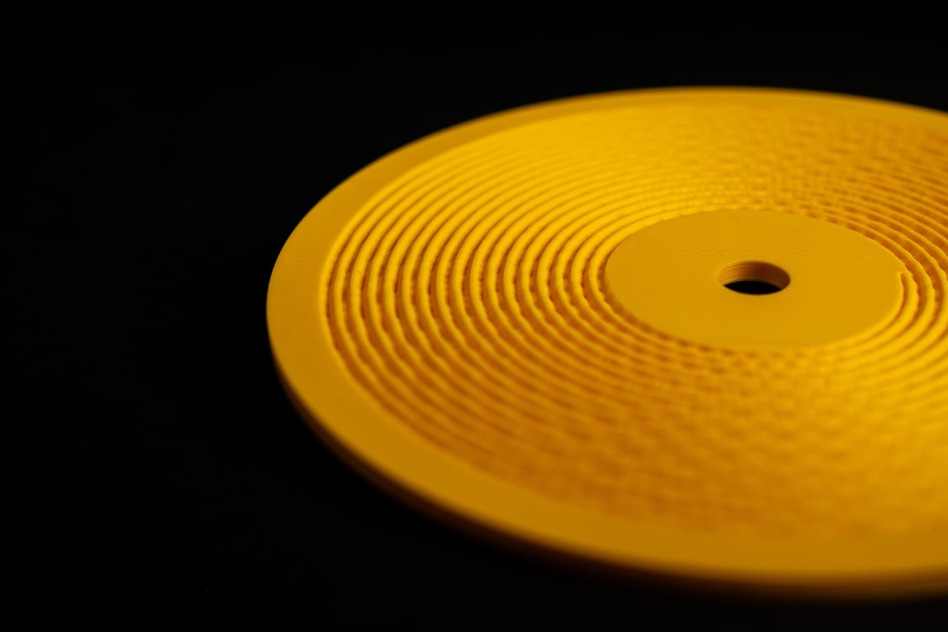 Close-up of a bright yellow 3D-printed Kräftsound disc showing the physical groove